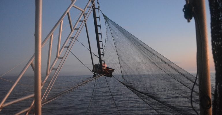 silhouette of trawl arm and net on shrimp boat in water