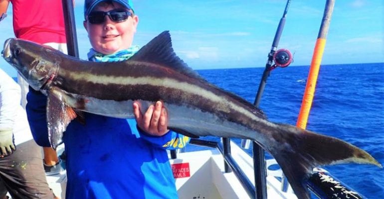 Fisherman holding a cobia on boat