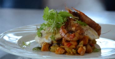 plated seafood dish with whole shrimp on top