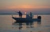 men fishing in boat at sunrise