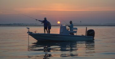 men fishing in boat at sunrise