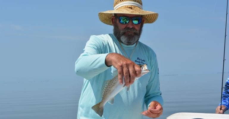 charter fisherman holding speckled trout