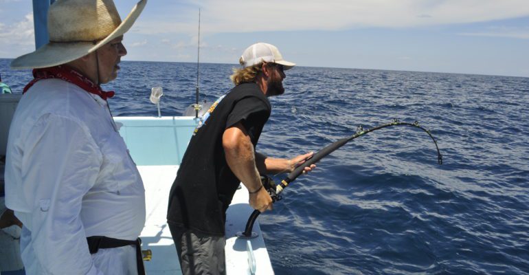 charter boat deckhand gets fish on line for customer